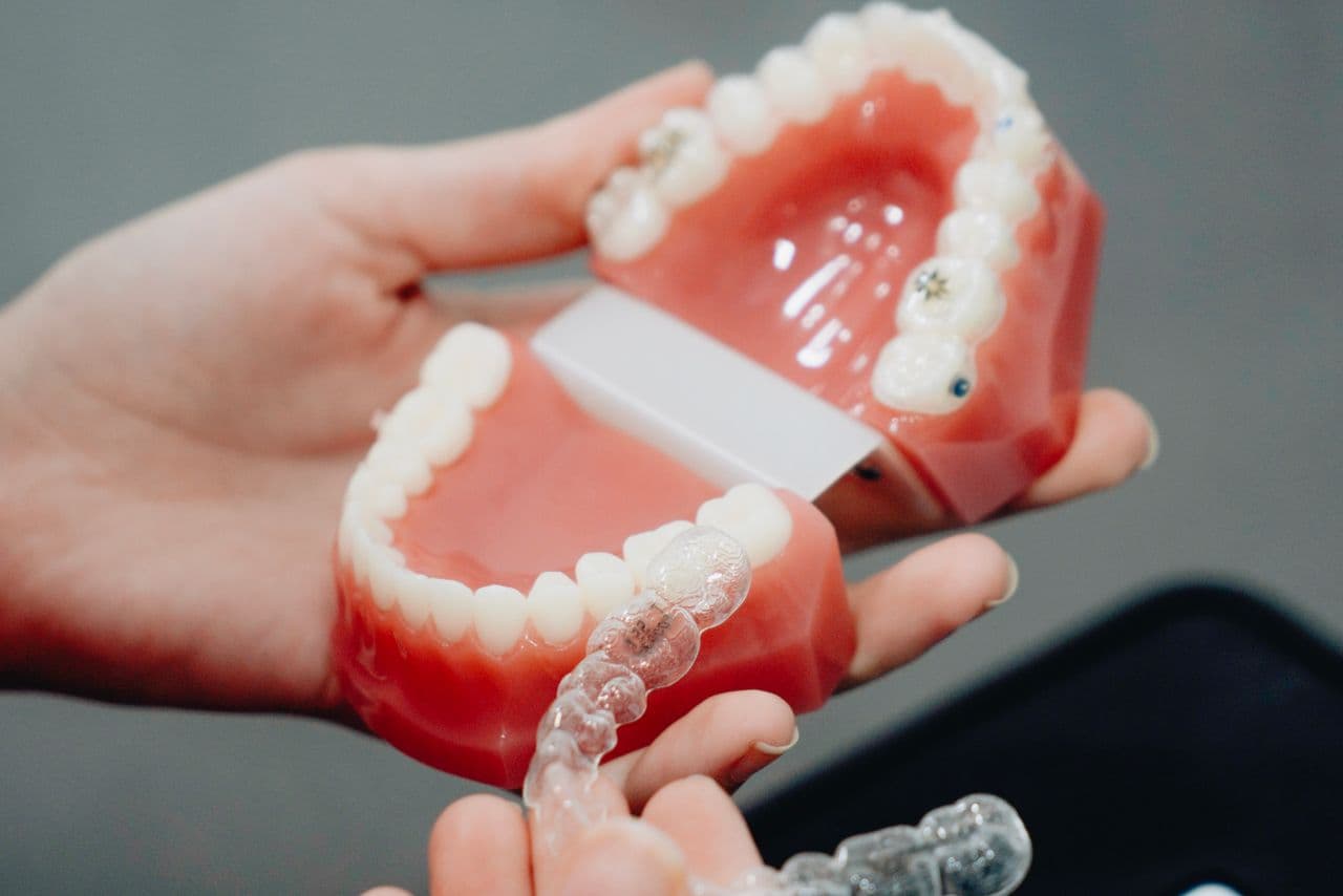 Clear custom night guard held beside a dental model of the teeth